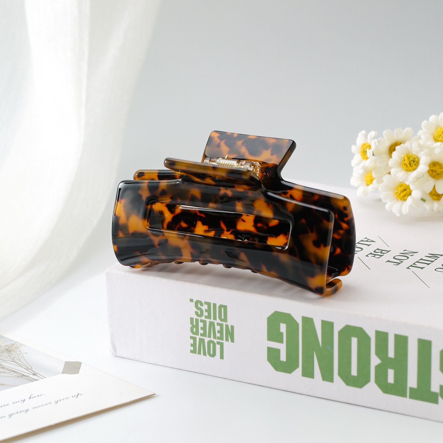 Polished tortoiseshell claw clip styled with white daisies
